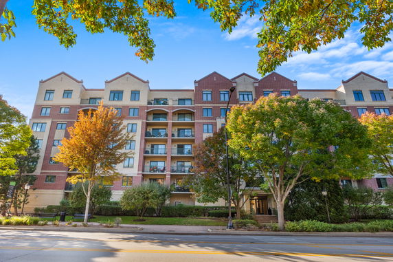 Front view of a multi-story apartment building with balconies and brick facade.