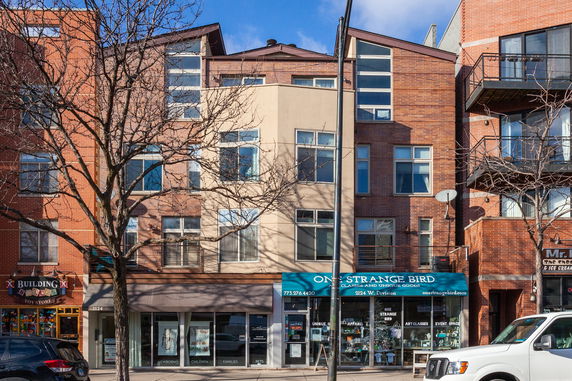 Front view of a multi-story building with retail shops on the ground floor.