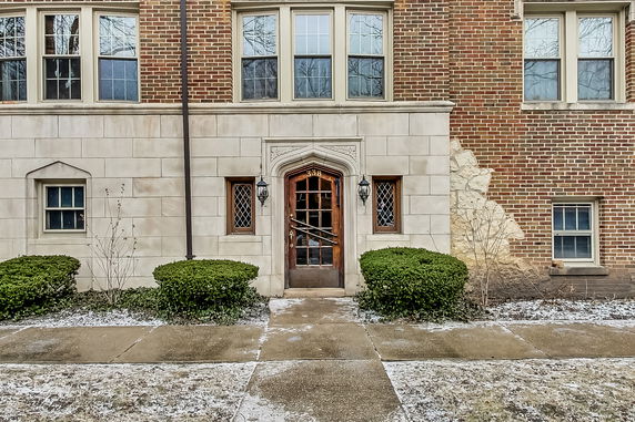 Front view of a brick building with large windows and decorative entrance.