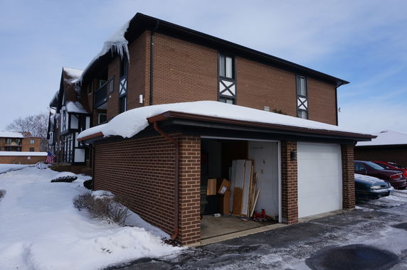 Front view of a two-story brick building with a garage under a snowy roof.