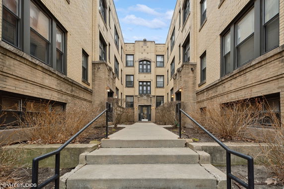 Front view of a multi-story brick apartment building with a central entrance.