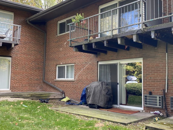 Rear view of a two-story brick house with balconies and sliding doors.