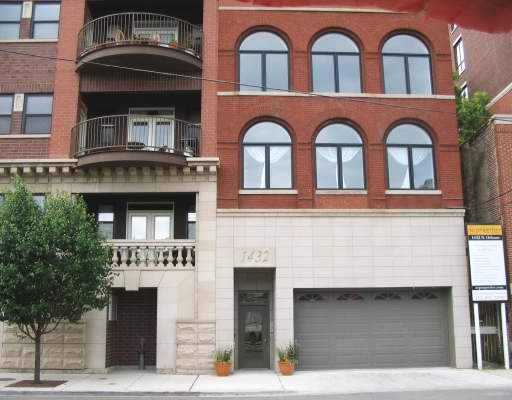 Front view of a multi-story brick building with large arched windows and a garage entrance.