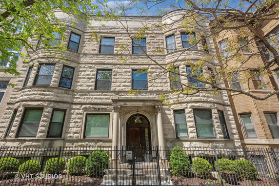 Front view of a multi-story stone building with large windows and an ornate entrance.