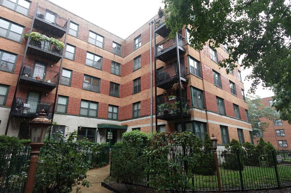 Front view of a multi-story brick apartment building with balconies.