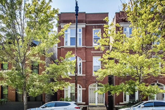 Front view of a three-story brick building with large windows.