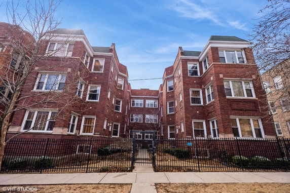 Front view of a multi-story brick building with gated entrance.