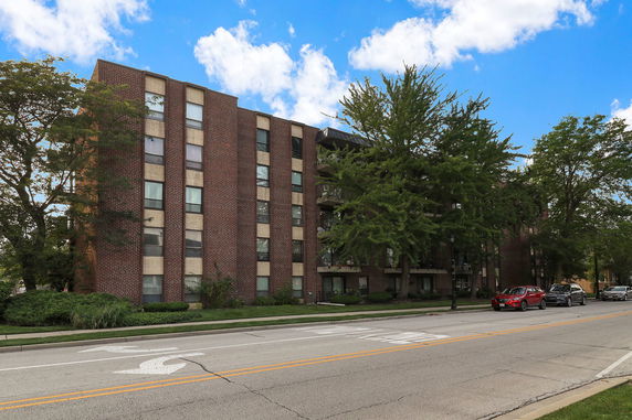 Front view of a multi-story brick apartment building on a road.