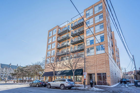 Front view of an apartment building with multiple balconies and large windows.
