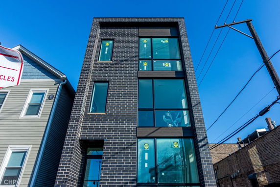 Front view of a modern multi-story building with large windows and brick facade.