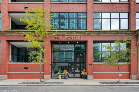 Front view of a multi-story brick building with large windows.