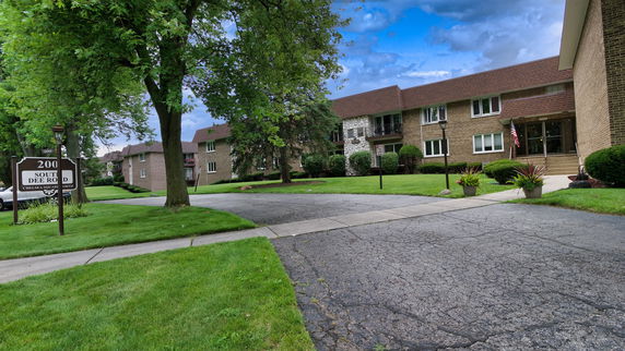 Front view of a two-story residential building with a brick facade and a paved walkway.