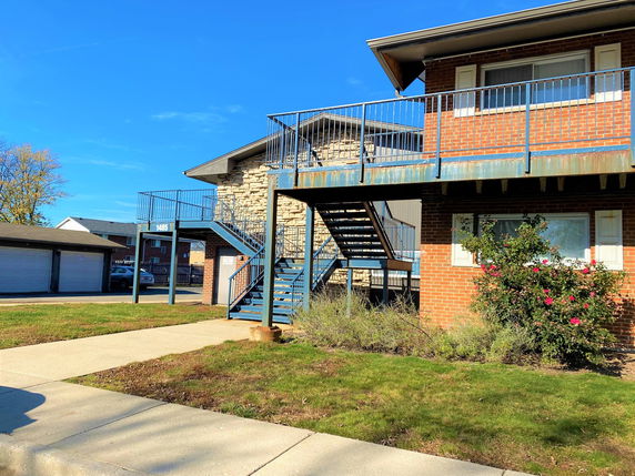 Front view of a two-story brick building with external stairs.