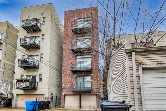 Front view of a multi-story building with balconies and garages.