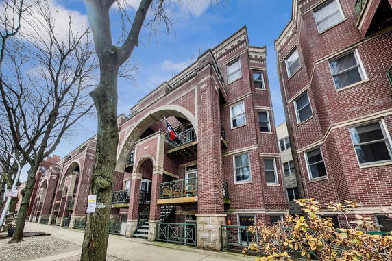 Front view of a multi-story brick building with decorative arches and balconies.