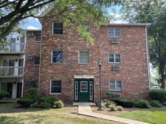 Front view of a multi-story brick building with multiple windows and a green entrance door.