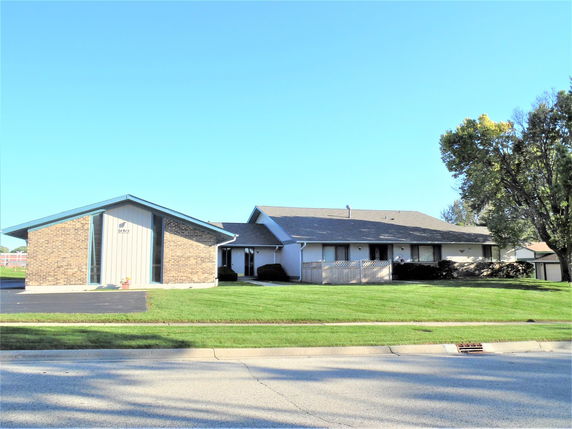 Front view of a one-story brick and siding house with a gabled roof.