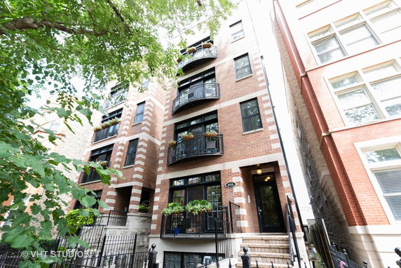 Front view of a multi-story brick building with balconies and black railings.