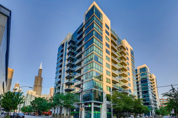 Front view of a multi-story apartment building with glass balconies.