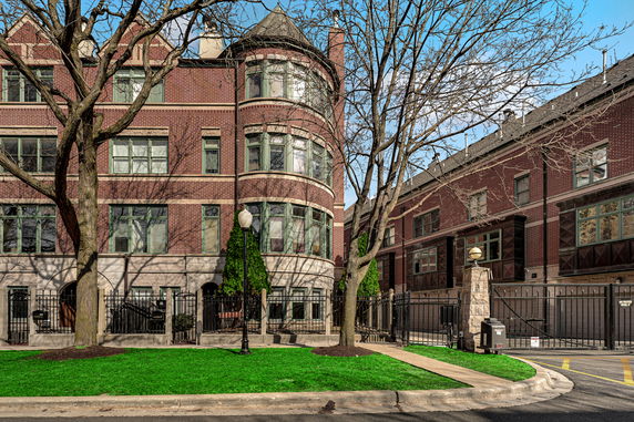 Front view of a multi-story brick building with large round windows and a gated entrance.