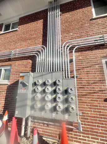 View of a brick building exterior with multiple utility meters and conduit pipes.