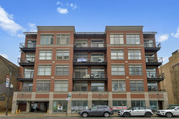 Front view of a multi-story brick building with balconies and large windows.