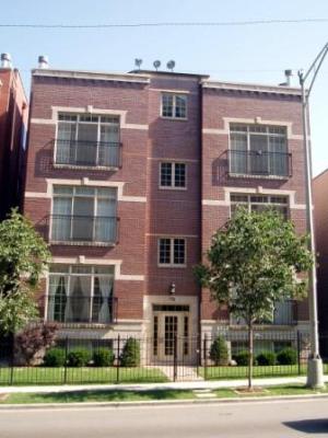 Front view of a four-story brick building with large windows and a central entrance.