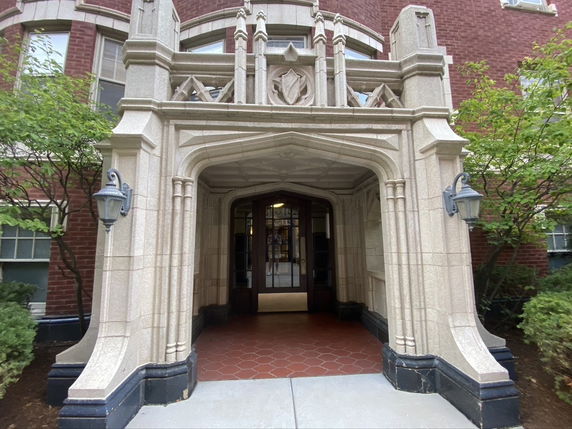 Front view of a building entrance with ornamental stone arch and decorative elements.