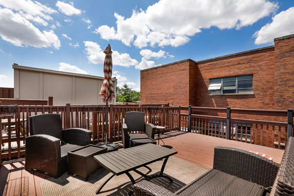 Rooftop deck with seating area and umbrella.
