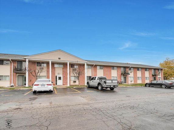 Front view of a two-story brick apartment building with a parking area.