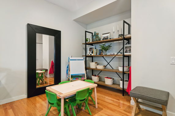 Small indoor play area with a children's table and chairs, mirror, and shelving unit.