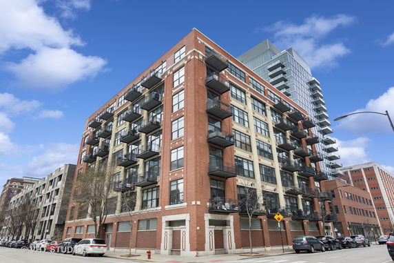 Front view of a brick multi-story apartment building with balconies.