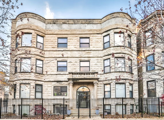 Front view of a three-story stone building with bay windows and a central entrance.