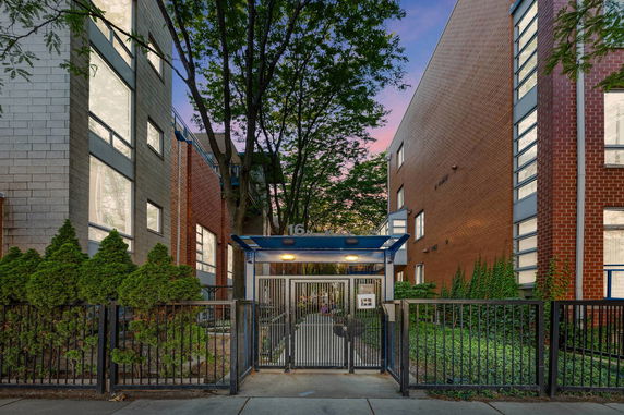 Front view of a multi-story residential building with a gated entrance.