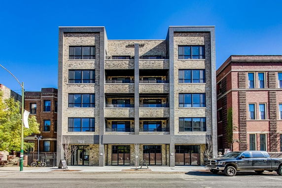 Front view of a multi-story brick building with large windows.
