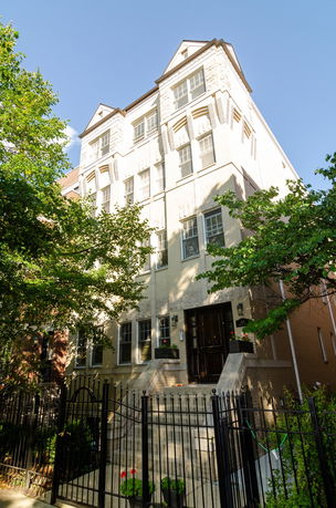 Front view of a multi-story building with a brick exterior and metal fence.