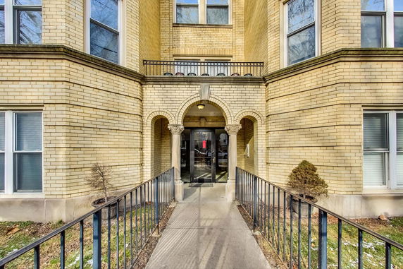 Front view of a building entrance with brick facade and arched doorway.
