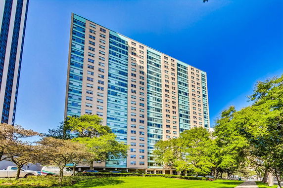 Front view of a tall residential building with multiple floors and a glass facade.