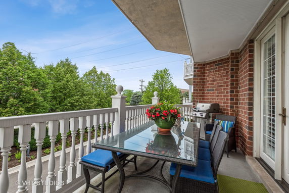 Outdoor balcony area with patio furniture and view of trees