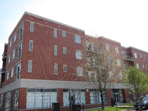 Front view of a multi-story brick building with retail space on the ground floor.