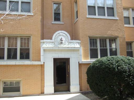 Front view of a brick building entrance with decorative elements above the door.