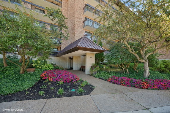 Front view of a multi-story building with balconies and landscaped entrance.