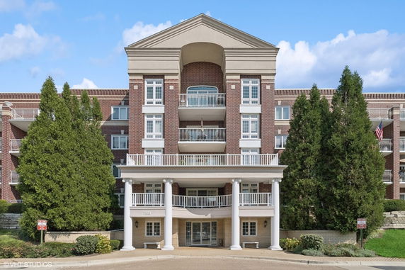 Front view of a multi-story brick building with balconies and a columned entrance.