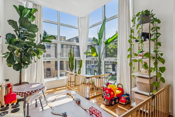Indoor play area with large windows, plants, and children's toys.