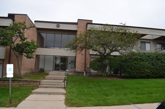 Front view of a two-story building with brick facade and large windows.