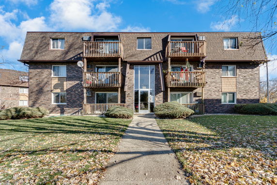 Front view of a three-story apartment building with balconies and a central entrance.