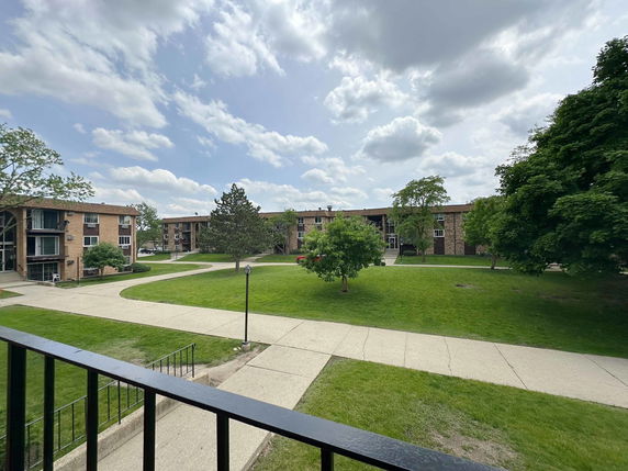 Panoramic view of residential buildings and green space from a balcony.