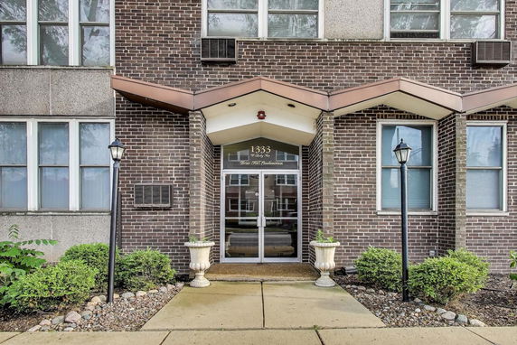 Front view of a brick building entrance with glass doors and decorative elements.