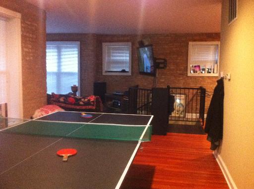 Indoor area with a table tennis setup and a television on the wall.