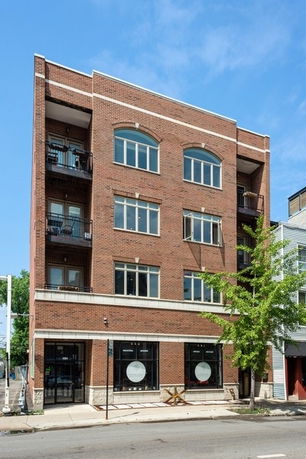 Front view of a multi-story brick building with large windows and balconies.